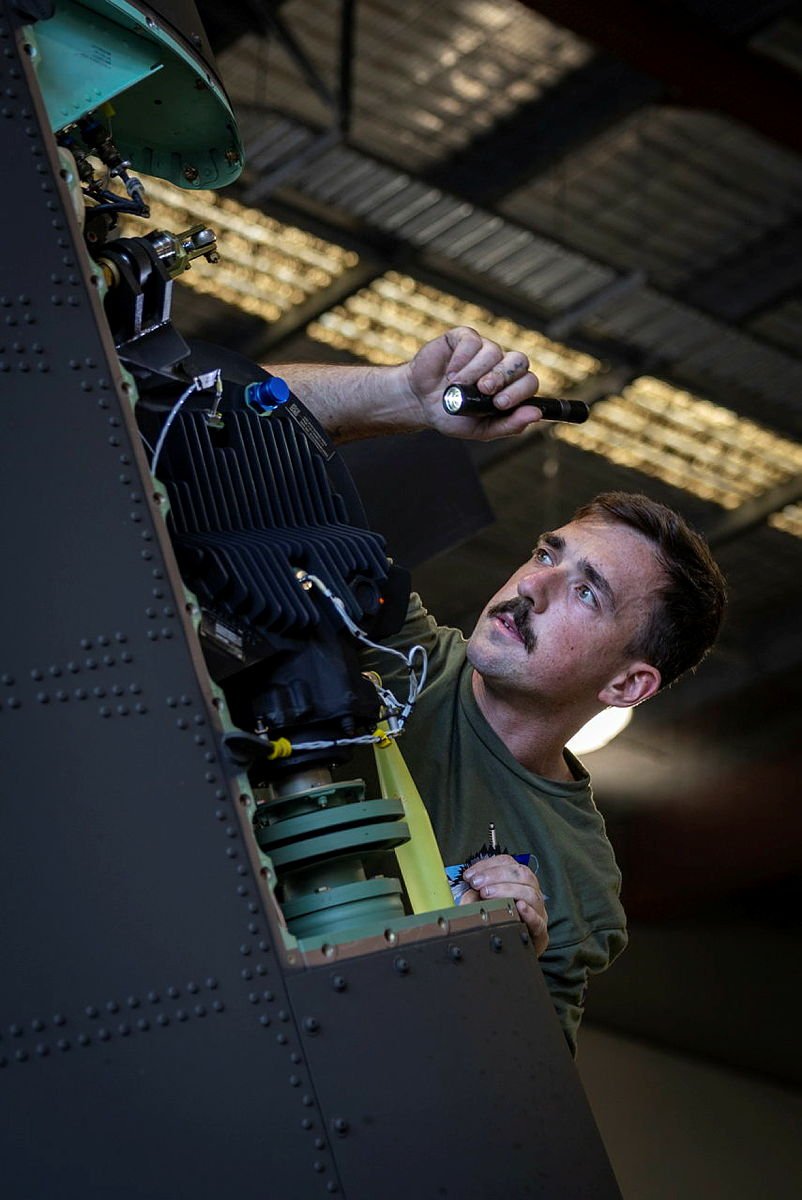 Royal Australian Air Force technicians conduct maintenance operations inside an aircraft hangar. (Photo: Australian Department of Defence)